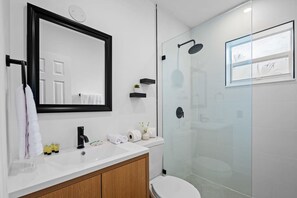 A modern bathroom with a white sink, black faucet, and a glass shower enclosure.
