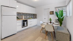 Una cocina moderna con armarios blancos, un salpicadero con diseño y un comedor con mesa y sillas.