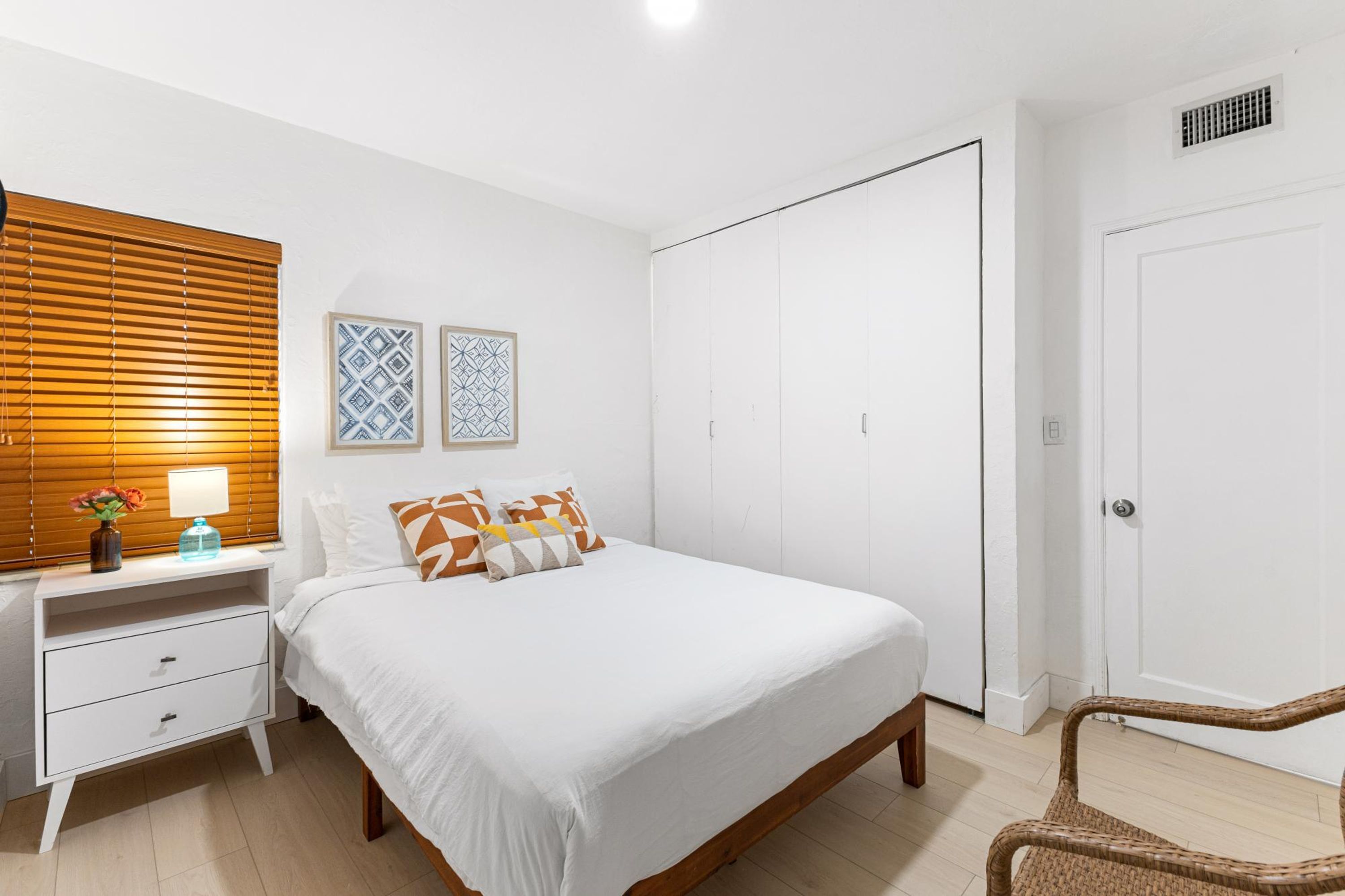 A bedroom with a bed, a nightstand, a dresser, a wardrobe, and a chair.