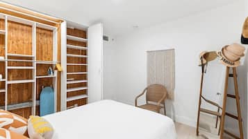 Un dormitorio con cama, armario, silla y escalera.
