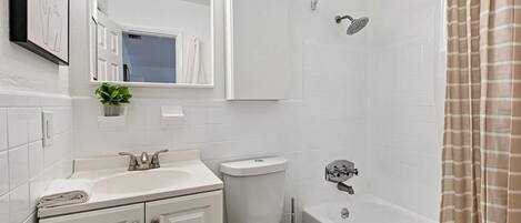 Une salle de bain moderne avec un lavabo, des toilettes et une baignoire, le tout de couleur blanche.