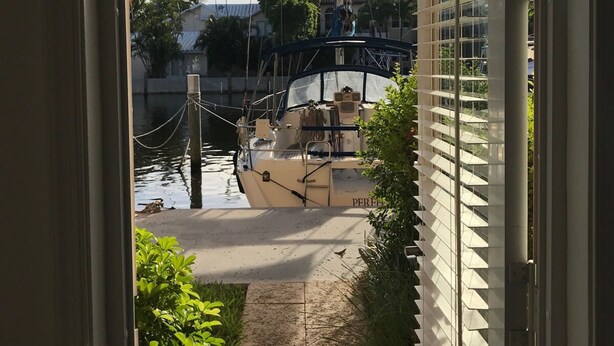 A view from a window overlooking a marina with boats docked, a bridge, and buildings in the background. - Las Olas Blvd Waterfront Apt (Fort Lauderdale)