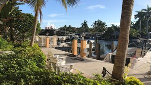 A marina with boats docked, palm trees, and a building with a white facade in the background. - Las Olas Blvd Waterfront Apt (Fort Lauderdale)