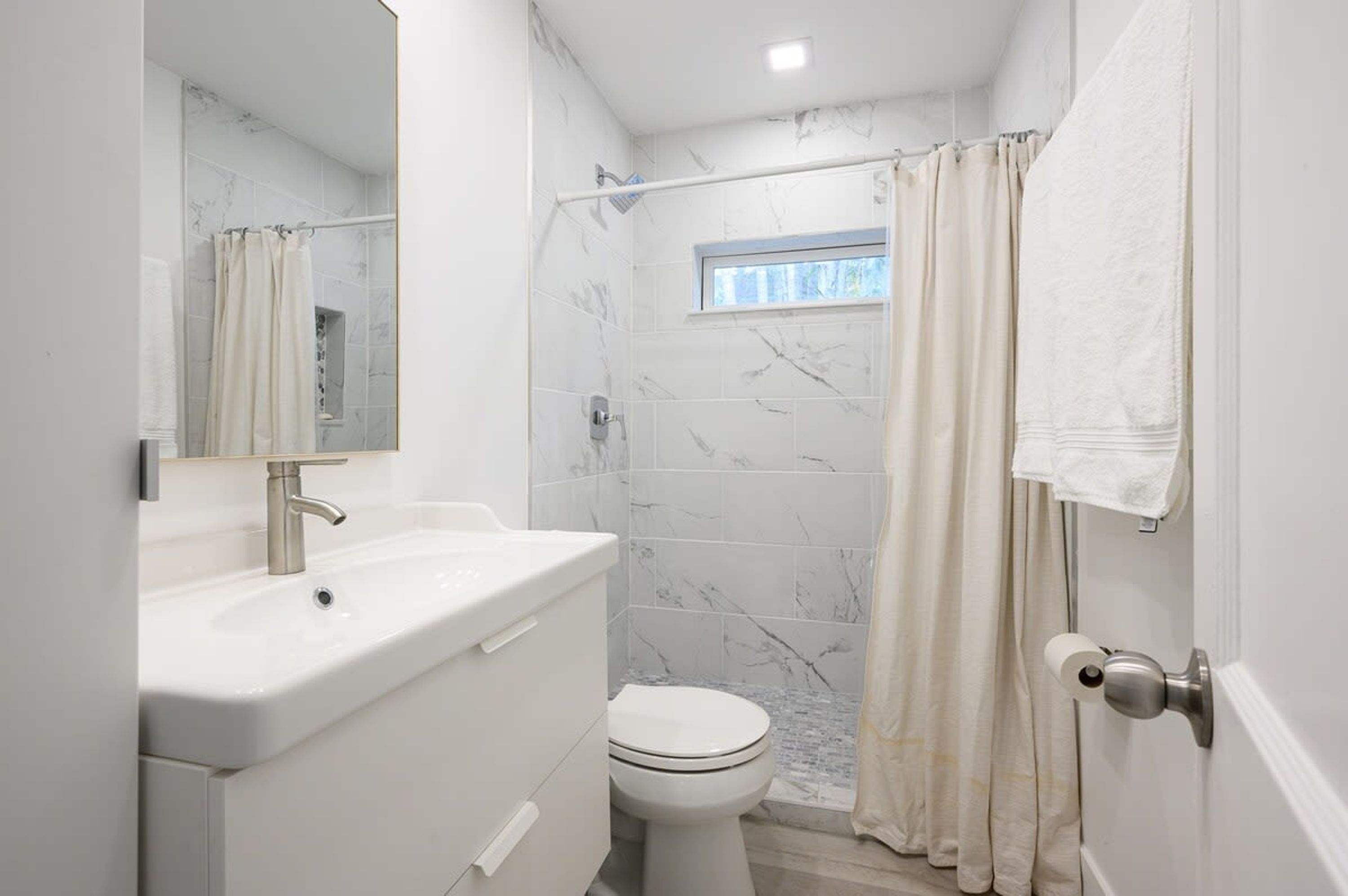 Une salle de bain avec un lavabo blanc, des toilettes et un rideau de douche.