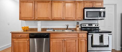 A kitchen with wooden cabinets, stainless steel appliances, a dishwasher, and a microwave.