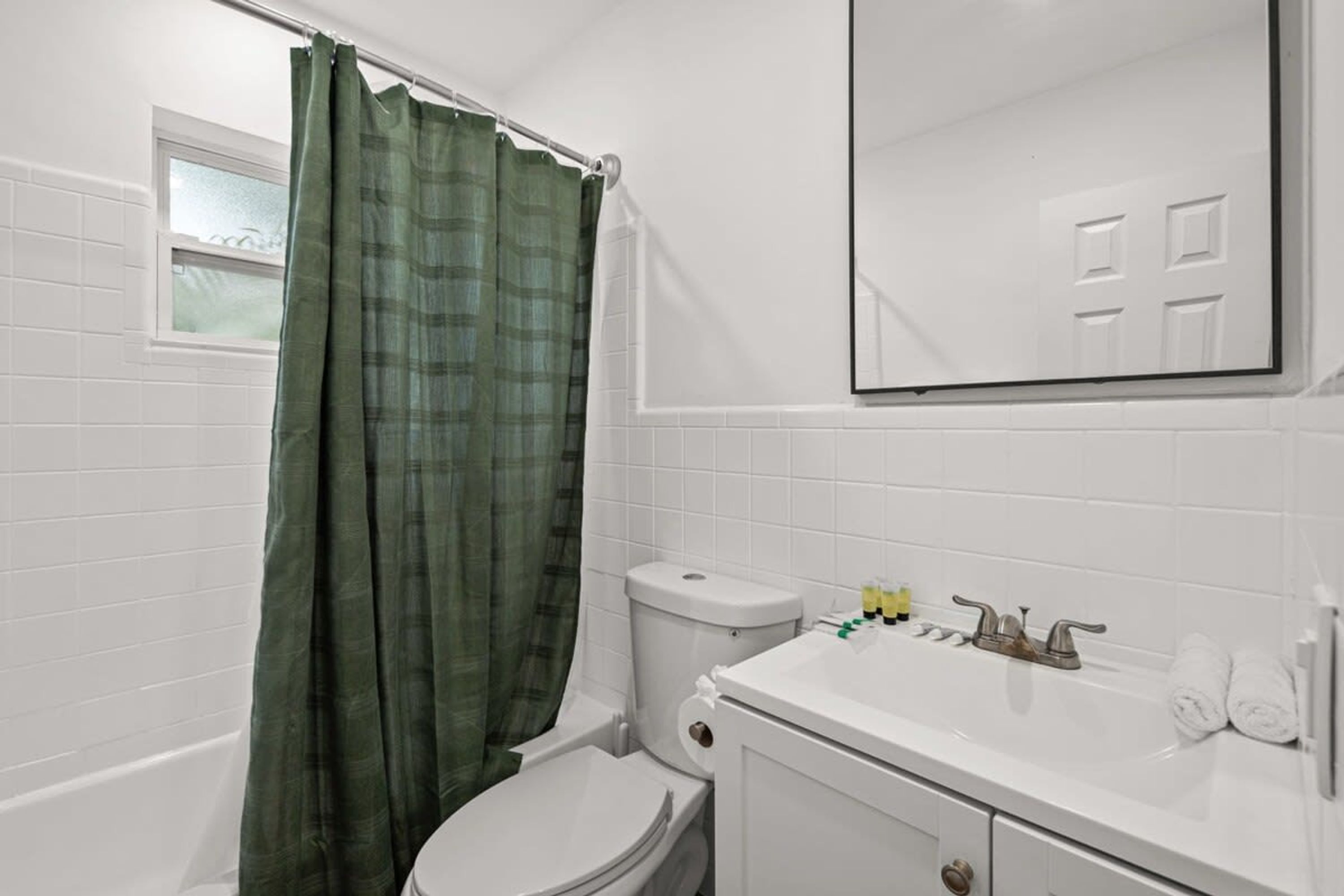 A bathroom with a toilet, sink, and green shower curtain.