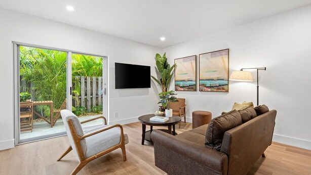 Una sala de estar moderna con un sofá, un sillón y un televisor de pantalla plana montado en la pared.