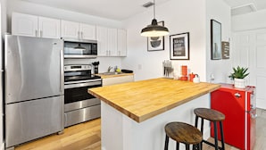 A modern kitchen with stainless steel appliances, a wooden island, and white cabinetry. - Lovely 2 BR Condo With Free Parking on Premises (Fort Lauderdale)