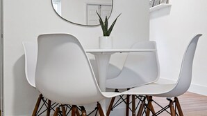 A dining area with a white table, two white chairs, a round mirror, and a potted plant. - Lake Ridge Villa - Free Parking (Fort Lauderdale)