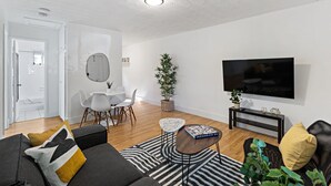 A modern living room with a sofa, a coffee table, a TV, and a dining area with chairs and a table. - Lake Ridge Villa - Free Parking (Fort Lauderdale)