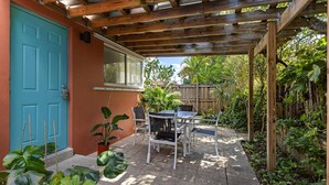 A patio with a wooden pergola, a table and chairs, and potted plants. - Lovely Studio With Great Location Free Parking (Fort Lauderdale)