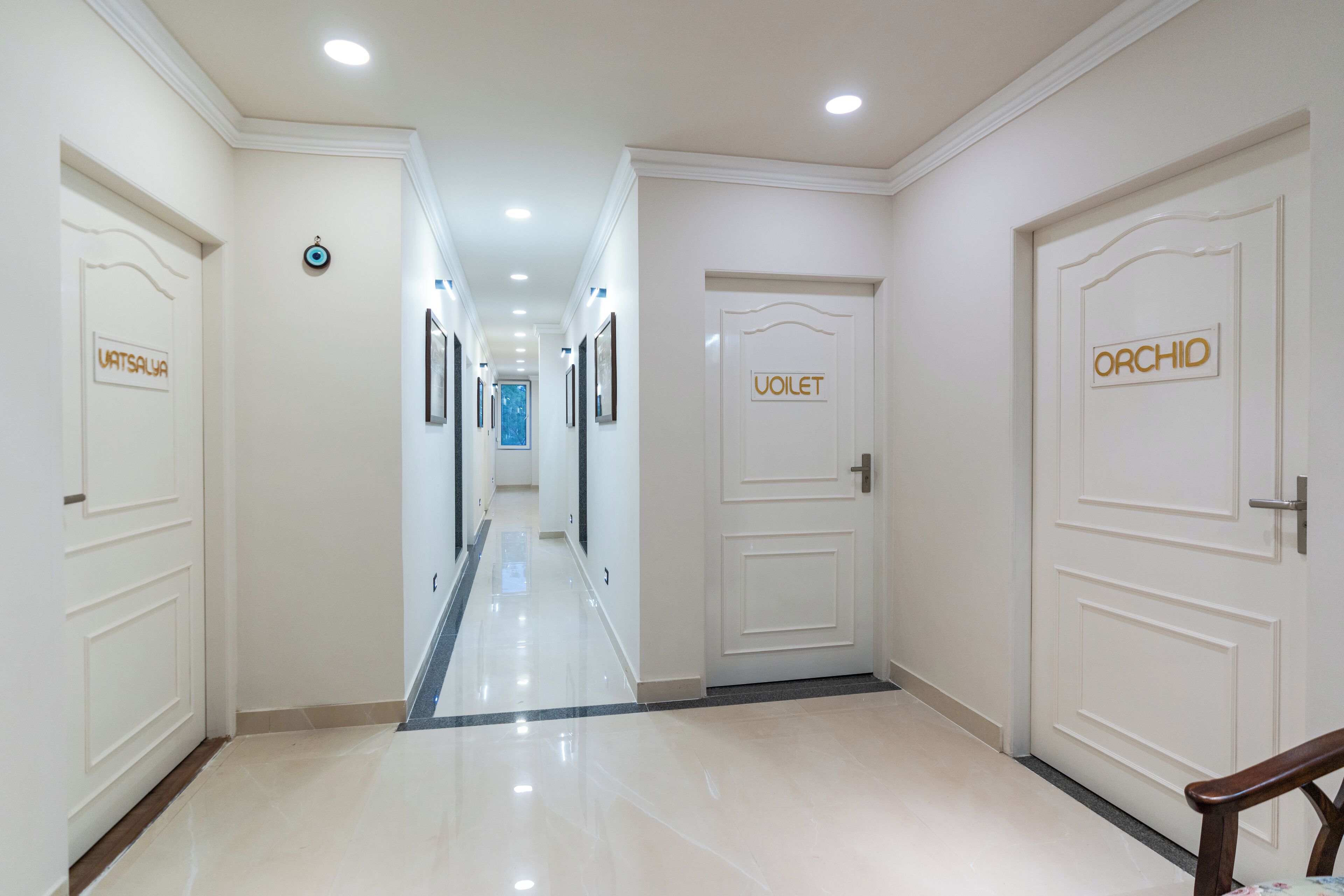 A hotel corridor with doors labeled 'VATSALYA,' 'VOILET,' and 'ORCHID.'