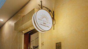 En hotellentrén med en skylt som visar texten ”BIRASA 1911 – ett unikt hotell”, en trappa och krukväxter.