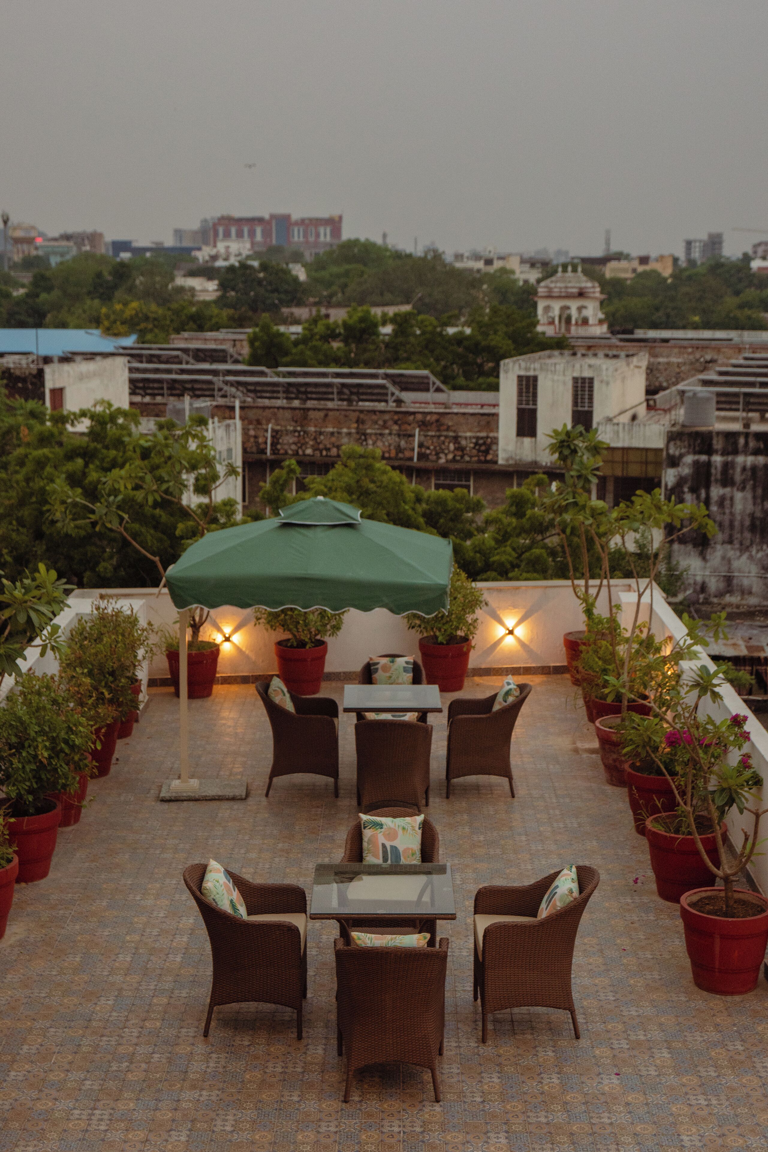 A rooftop terrace with outdoor seating, potted plants, and a view of the cityscape.