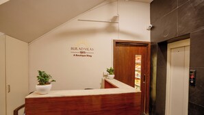 En receptionsdisk med träpanel, en krukväxt och en väggskylt med texten: ”BIRAD VILAS 1911 – ett unikt hotell”.