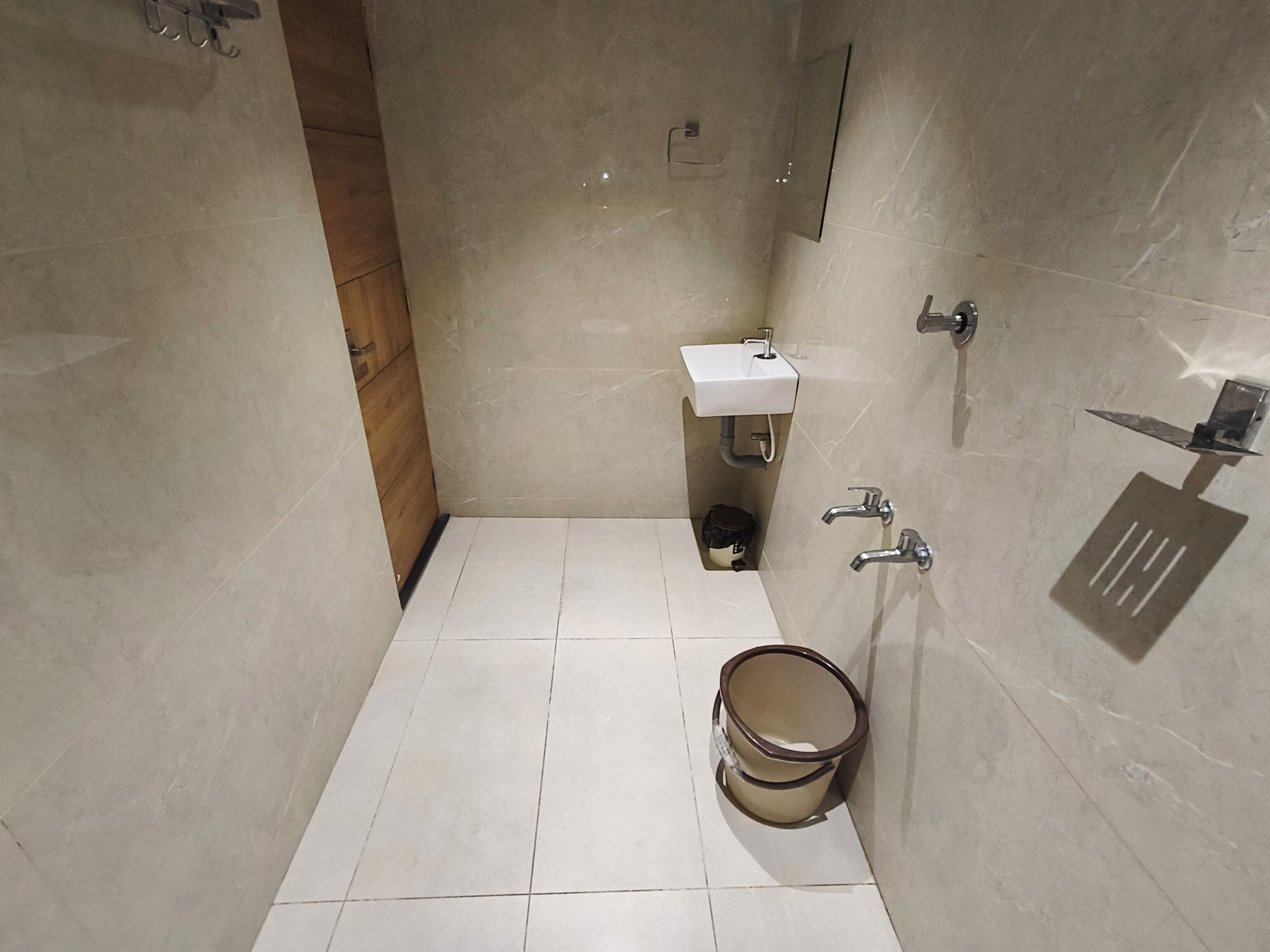 A small, tiled bathroom with a sink, two faucets, and a toilet.
