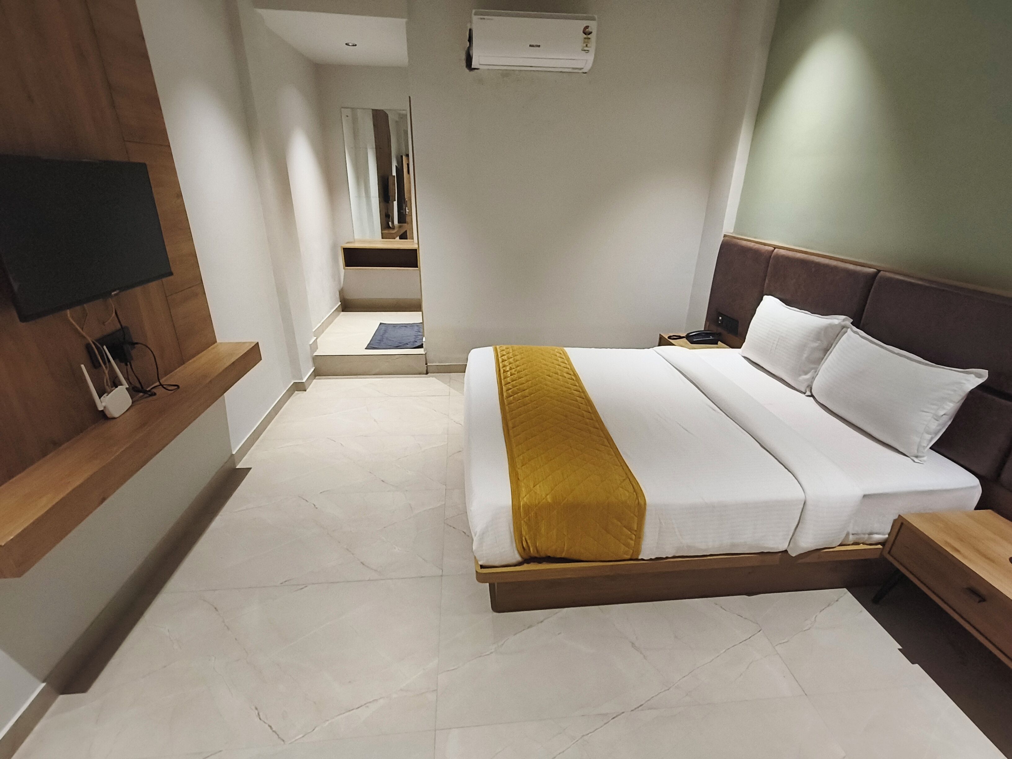 Une chambre d’hôtel équipée d’un lit, de tables de chevet, d’un téléviseur fixé au mur et d’un appareil de climatisation.
