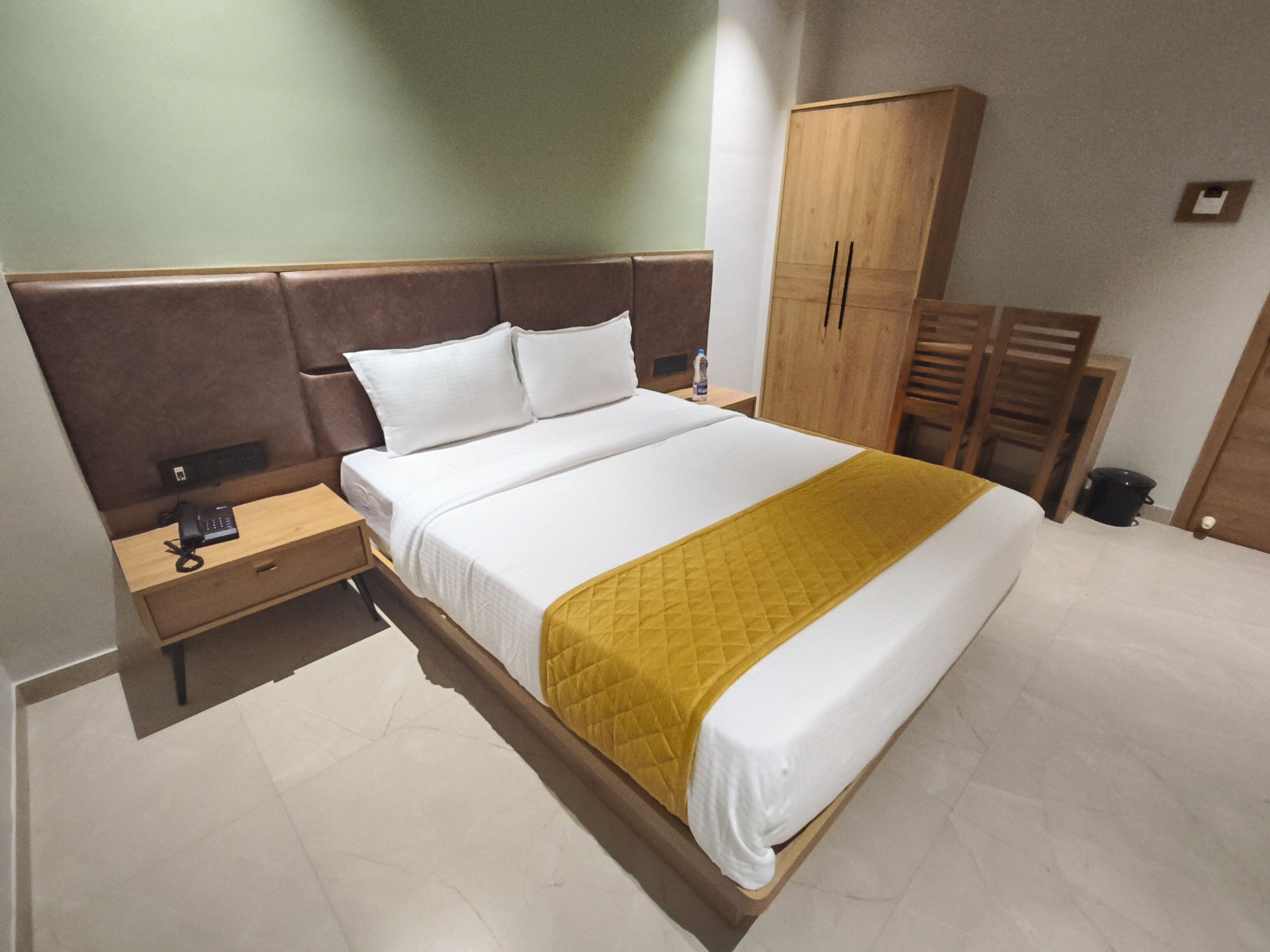 Una camera d'albergo con un letto, un comodino, un armadio e un piccolo tavolino.