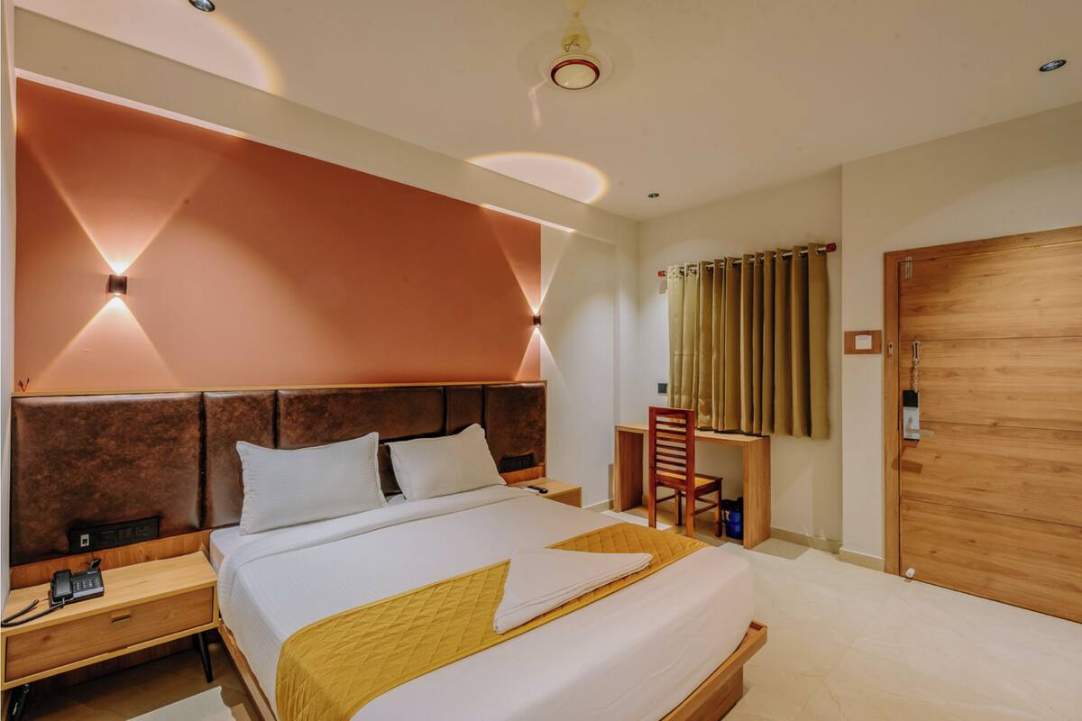 A hotel room with a large bed, bedside tables, a desk, and a wooden wardrobe.