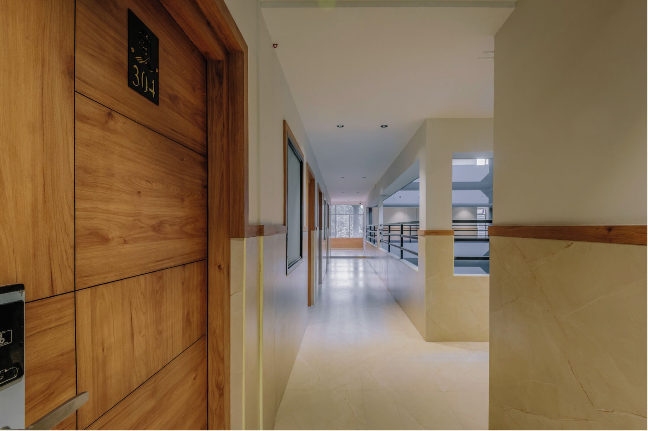 Corredor moderno com lambris de madeira, piso ladrilhado e vista para uma varanda.