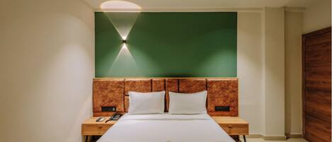 Una habitación de hotel moderna con una cama grande, cabecera de madera y una pared de acento verde.