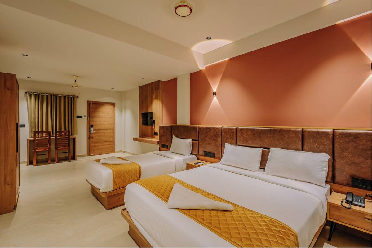 A hotel room with two beds, a desk, and a chair.