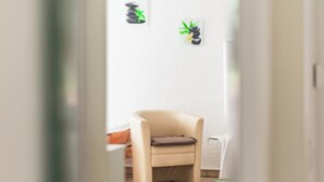 A hallway with a beige chair, a small plant, and a white wall. - Platanenweg vacation apartment, perfect for up to 4 people (Alsbach-Hähnlein)