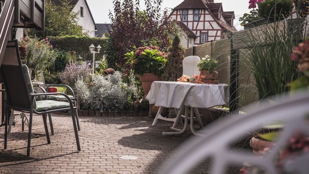 A patio area with a table and chairs, surrounded by potted plants and a brick floor. - Platanenweg vacation apartment, perfect for up to 4 people (Alsbach-Hähnlein)