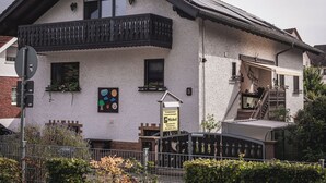 A two-story building with a balcony, a signboard, and a staircase leading to an upper floor. - Platanenweg vacation apartment, perfect for up to 4 people (Alsbach-Hähnlein)