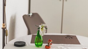 A round table with a white tablecloth, a green glass bottle, a small red figurine, and a white flower. - Platanenweg vacation apartment, perfect for up to 4 people (Alsbach-Hähnlein)
