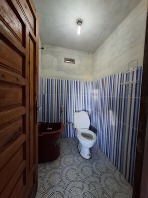 Un baño pequeño con inodoro, lavamanos y zona de ducha.
