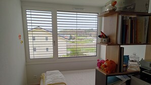 A small bedroom with a single bed, a window with blinds, a desk with a printer, and a bookshelf. - Room in our family home, close to the station and services (Courtepin)