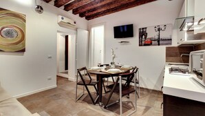 A dining area with a round table, chairs, and a TV mounted on the wall. - I Quattro Mori by Wonderful Italy (Venice)