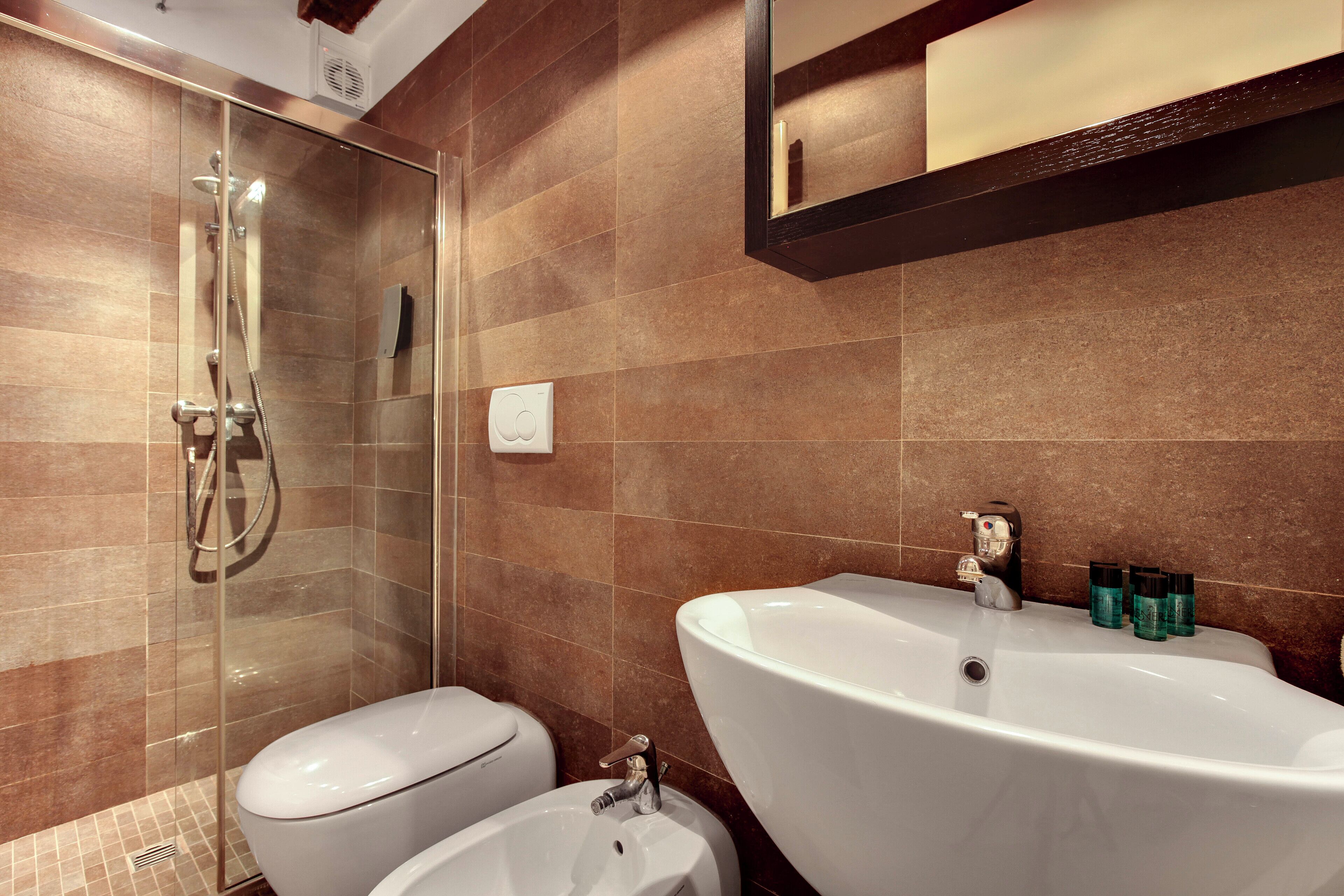 A modern bathroom with a glass-enclosed shower, a large white sink, and a toilet.