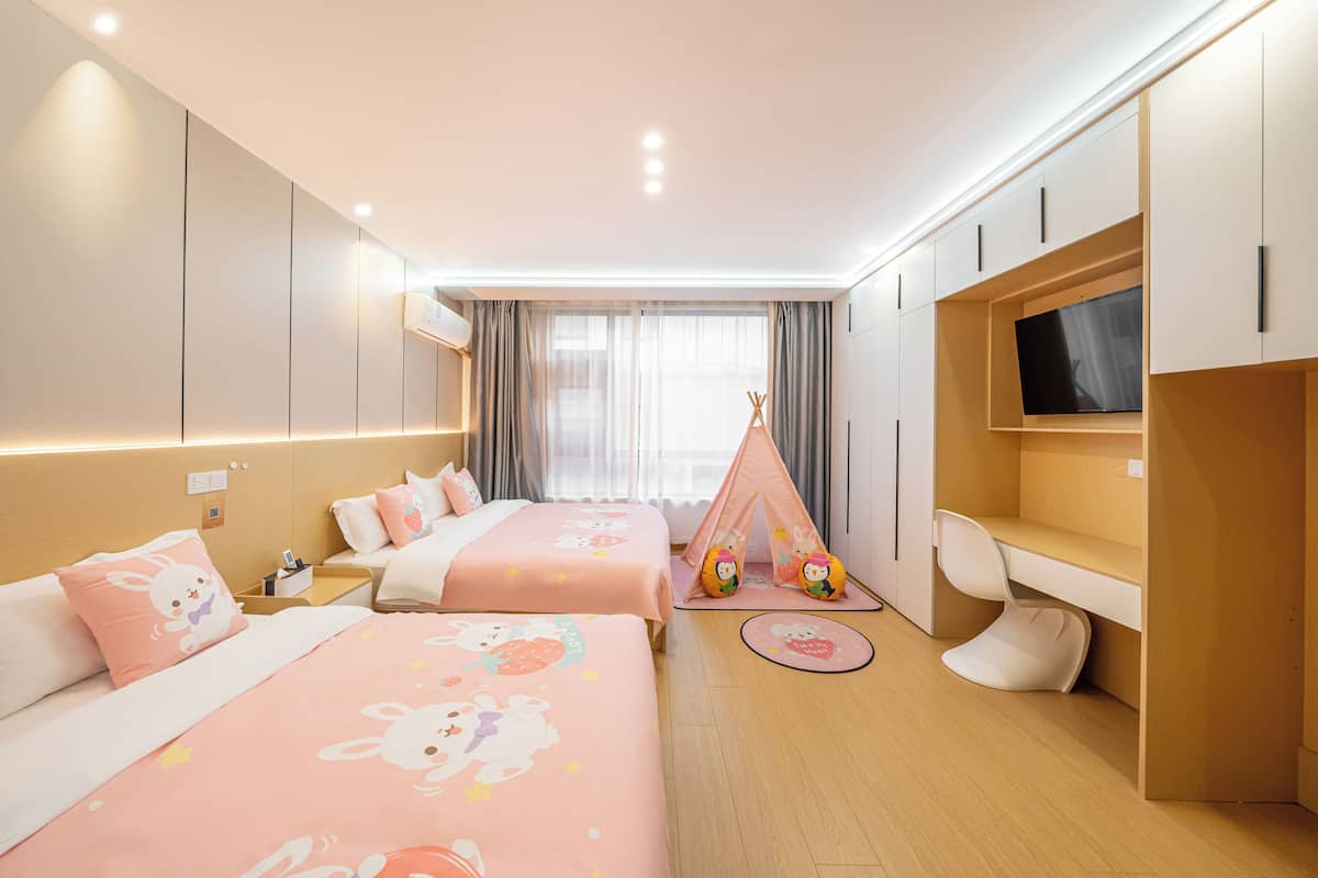 A hotel room with two beds, a TV, a desk, and a tent.
