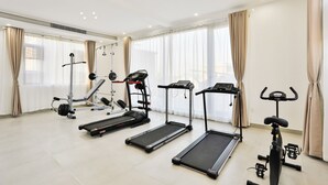 Une salle de sport équipée de tapis de course, d’un vélo d’appartement et d’un banc de musculation.