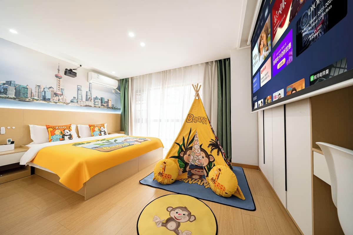 A hotel room with a bed, a yellow bedspread, a teepee, and a wall-mounted TV.