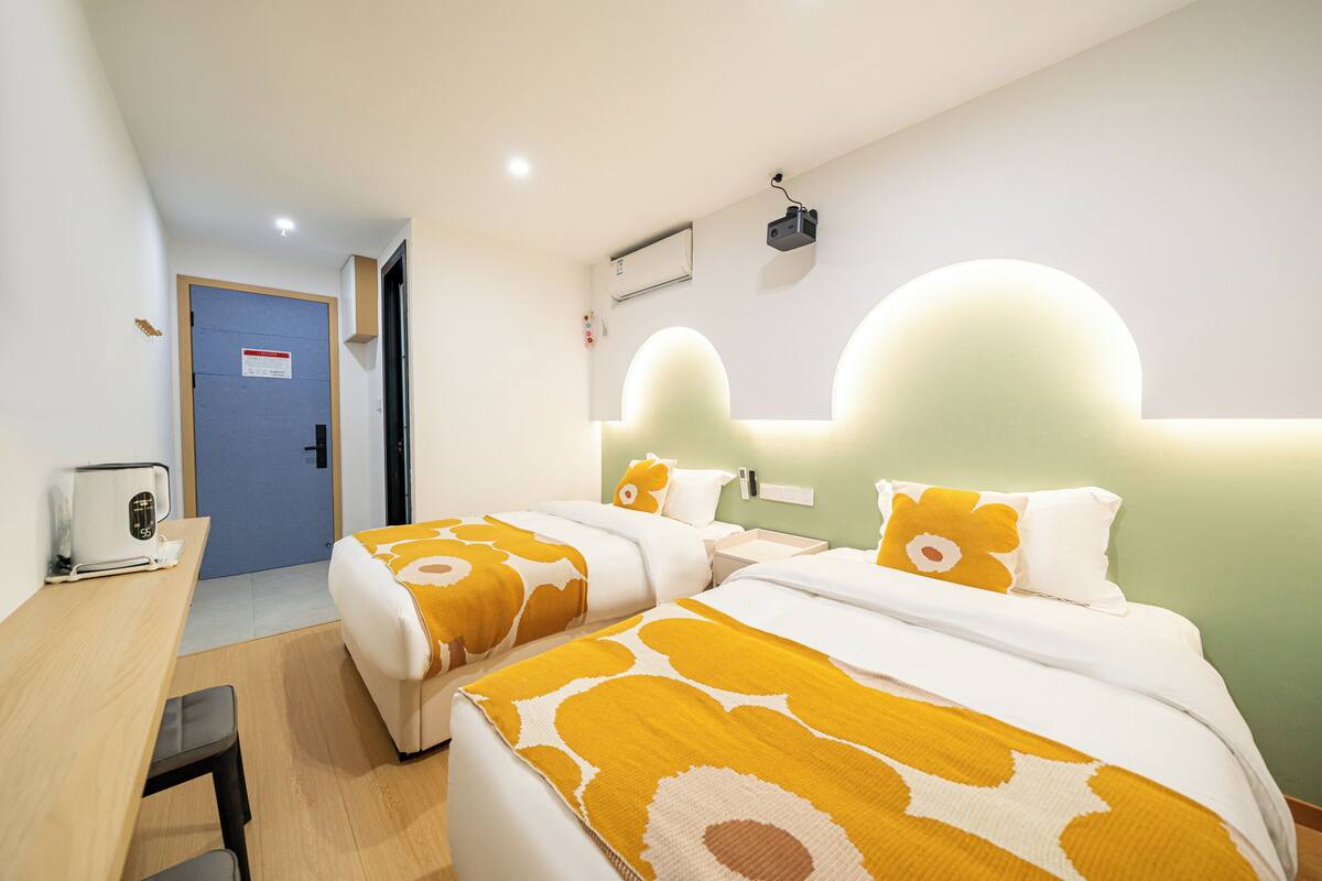 A hotel room with two beds, a desk, and a chair.
