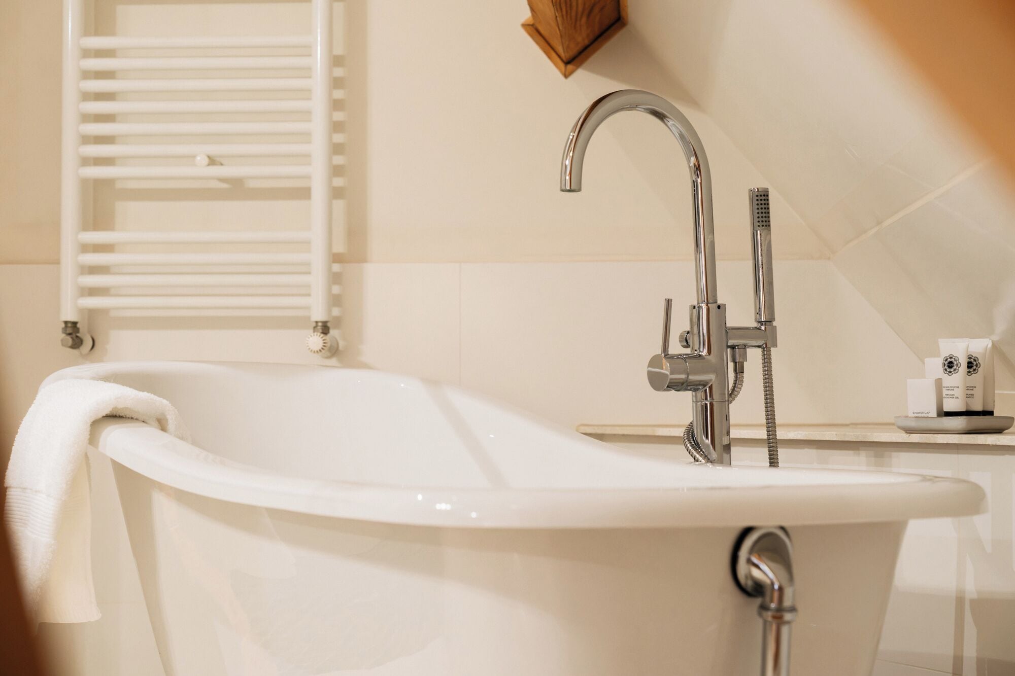 A modern bathroom with a freestanding bathtub, a wall-mounted towel rack, and a small shelf with toiletries.
