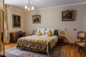 Habitación de hotel con una cama grande, dos mesitas de noche, una silla y tres cuadros en las paredes.