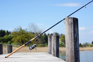 A fishing rod on a wooden dock extending into a body of water, surrounded by trees and greenery. - Hotel Les Deux Chevres Gevrey-Chambertin (Gevrey-Chambertin)