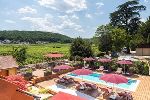 A poolside area with lounge chairs and umbrellas, surrounded by a wooden deck and a view of a vineyard. - Hotel Les Deux Chevres Gevrey-Chambertin (Gevrey-Chambertin)