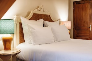 A neatly made bed with white linens and pillows, a wooden door, and two bedside lamps with patterned shades. - Hotel Les Deux Chevres Gevrey-Chambertin (Gevrey-Chambertin)