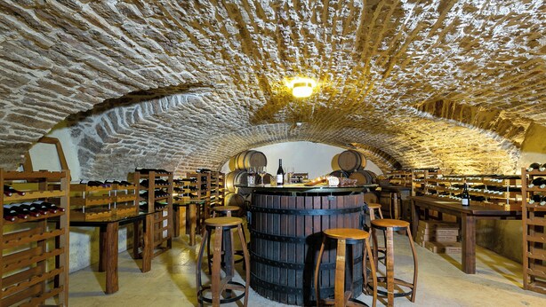 A wine cellar with wooden barrels, wine racks, and stools. - Hotel Les Deux Chevres Gevrey-Chambertin (Gevrey-Chambertin)