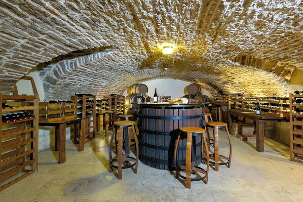 A wine cellar with wooden barrels, wine racks, and stools. - Hotel Les Deux Chevres Gevrey-Chambertin (Gevrey-Chambertin)