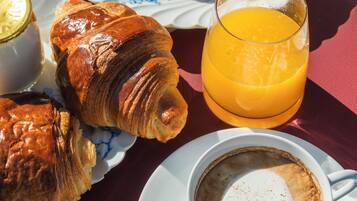A breakfast setting with croissants, fruit, and a cup of coffee.