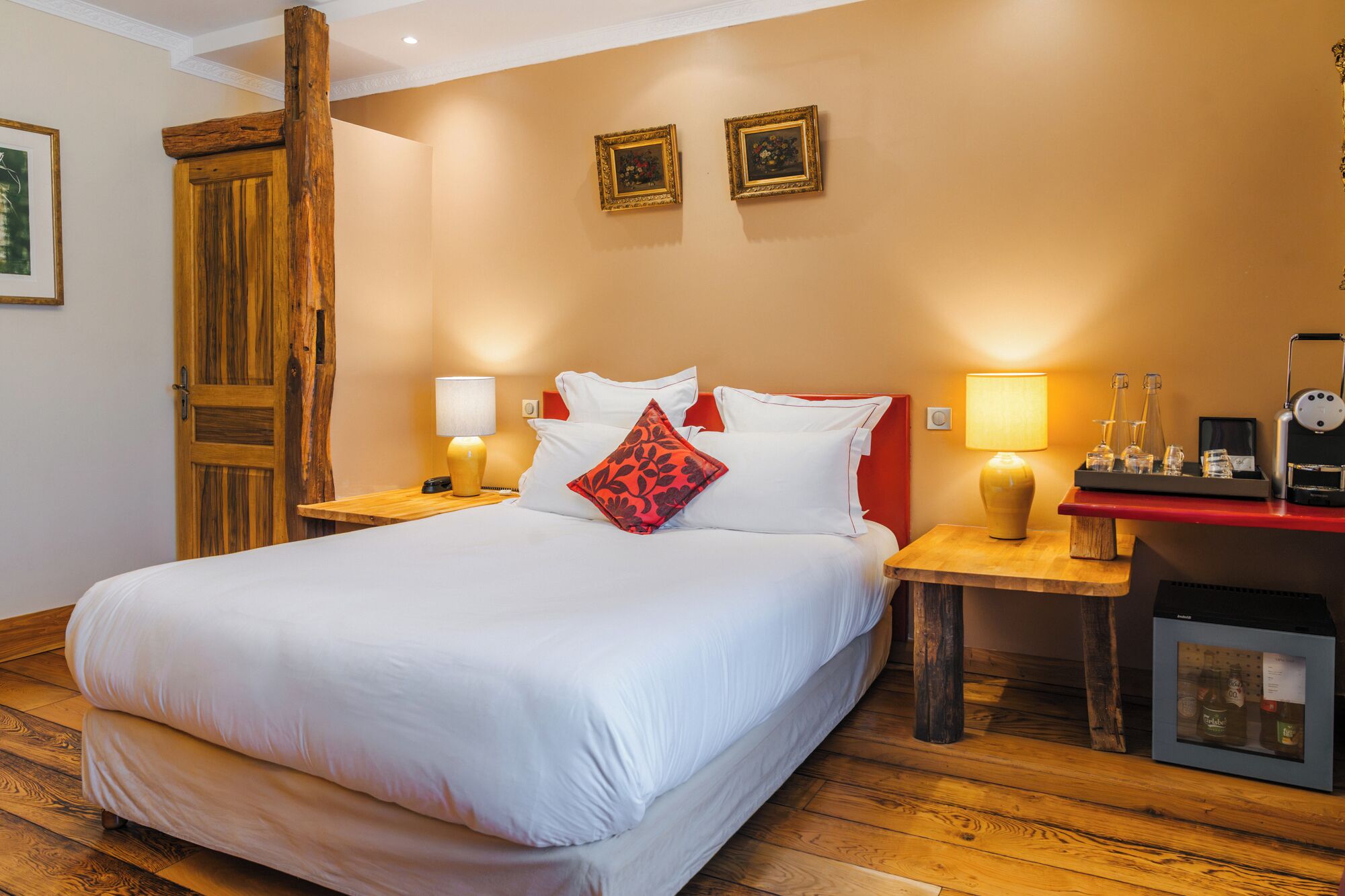 Habitación de hotel con una cama grande, dos mesitas de noche, una mesita de madera, un escritorio con una computadora y un minibar.