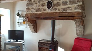 A cozy living room with a stone fireplace, a television, and a red chair. - Quiet country house  (Le Buisson)