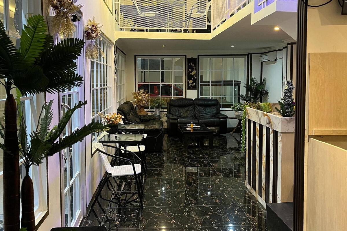 A spacious indoor area with a black marble floor, a seating area with a sofa and chairs, and a balcony with a railing.
