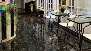 A spacious dining area with a black marble floor, large windows, and a high ceiling. - Rafithahotel (Baturetno)